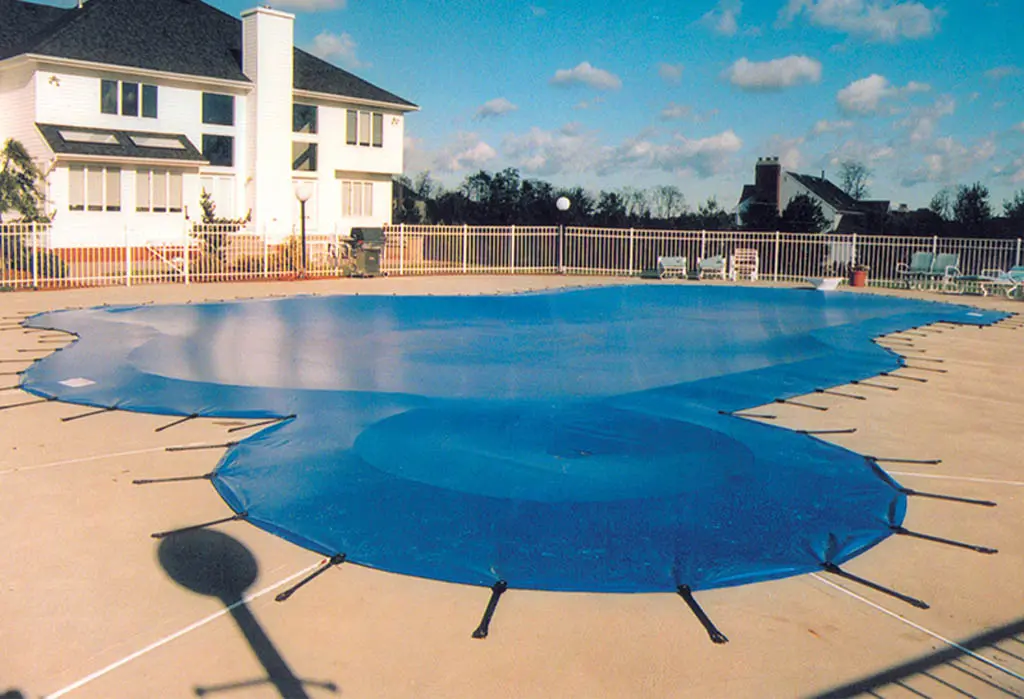Blue rectangular pool safety cover installed at residential property