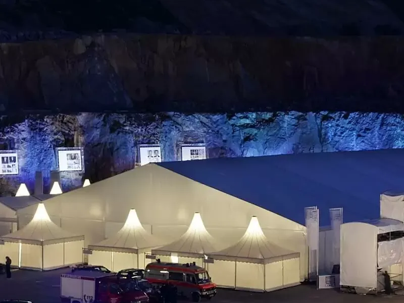 Illuminated event tents set up indoors with blue and purple stage lighting.