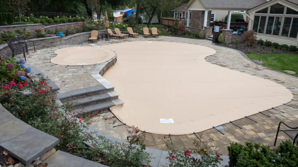 Another tan pool safety cover secured around a residential pool.