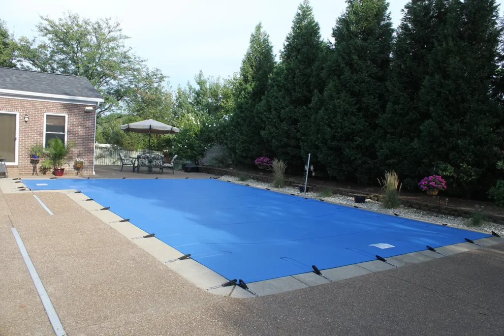 Blue pool safety cover stretched across residential pool.