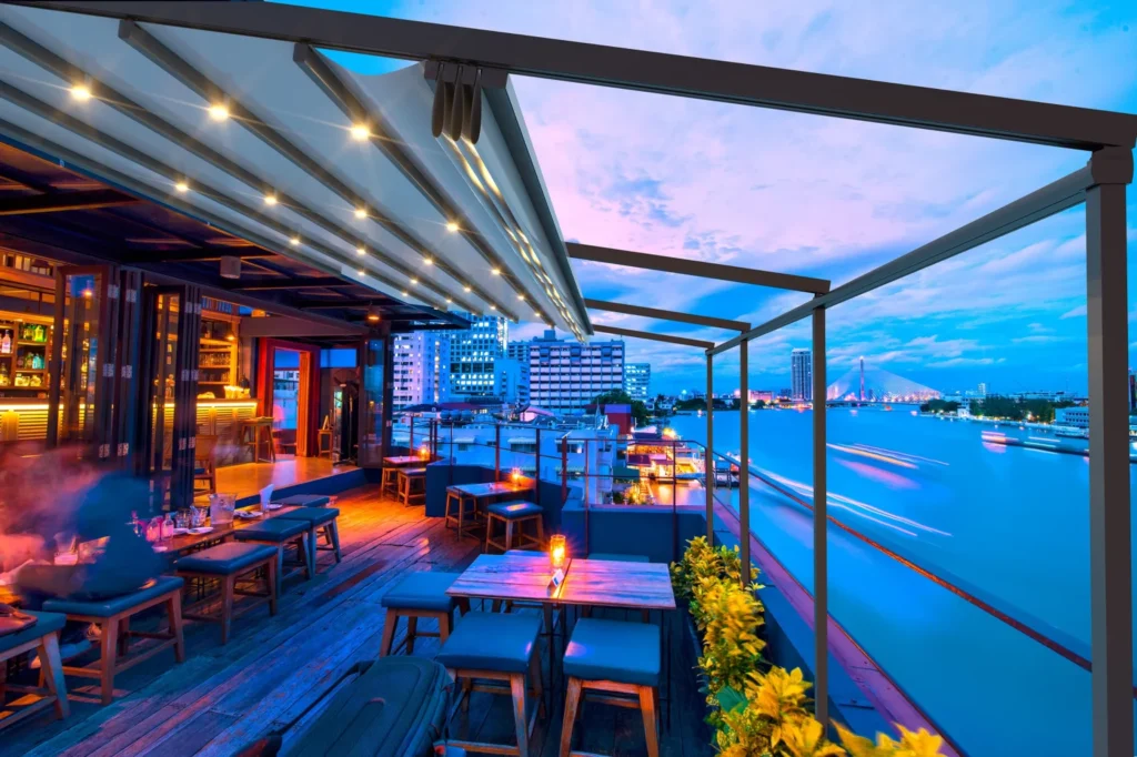 Outdoor restaurant terrace with retractable pergola and night lighting.