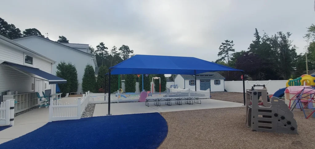 Blue canopy tent covering poolside seating in a residential backyard.