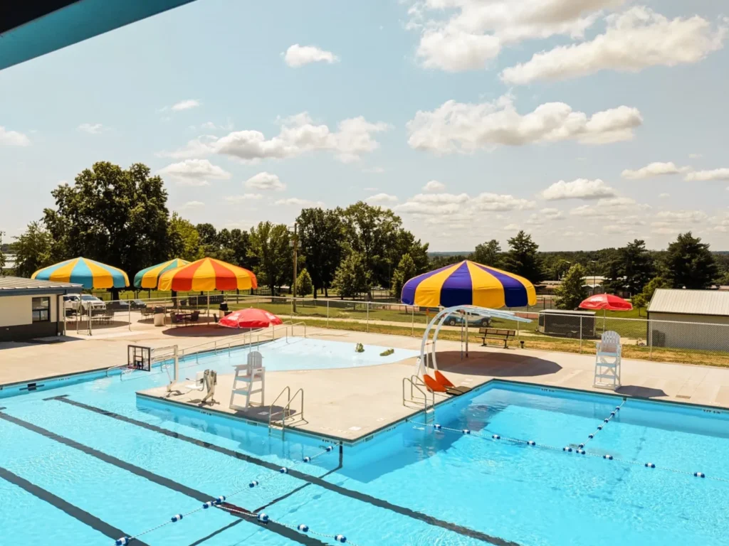 Poolside with yellow, blue, and red umbrellas shading tables and chairs.