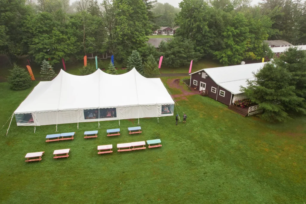 Outdoor festival tents with picnic benches on green grass.